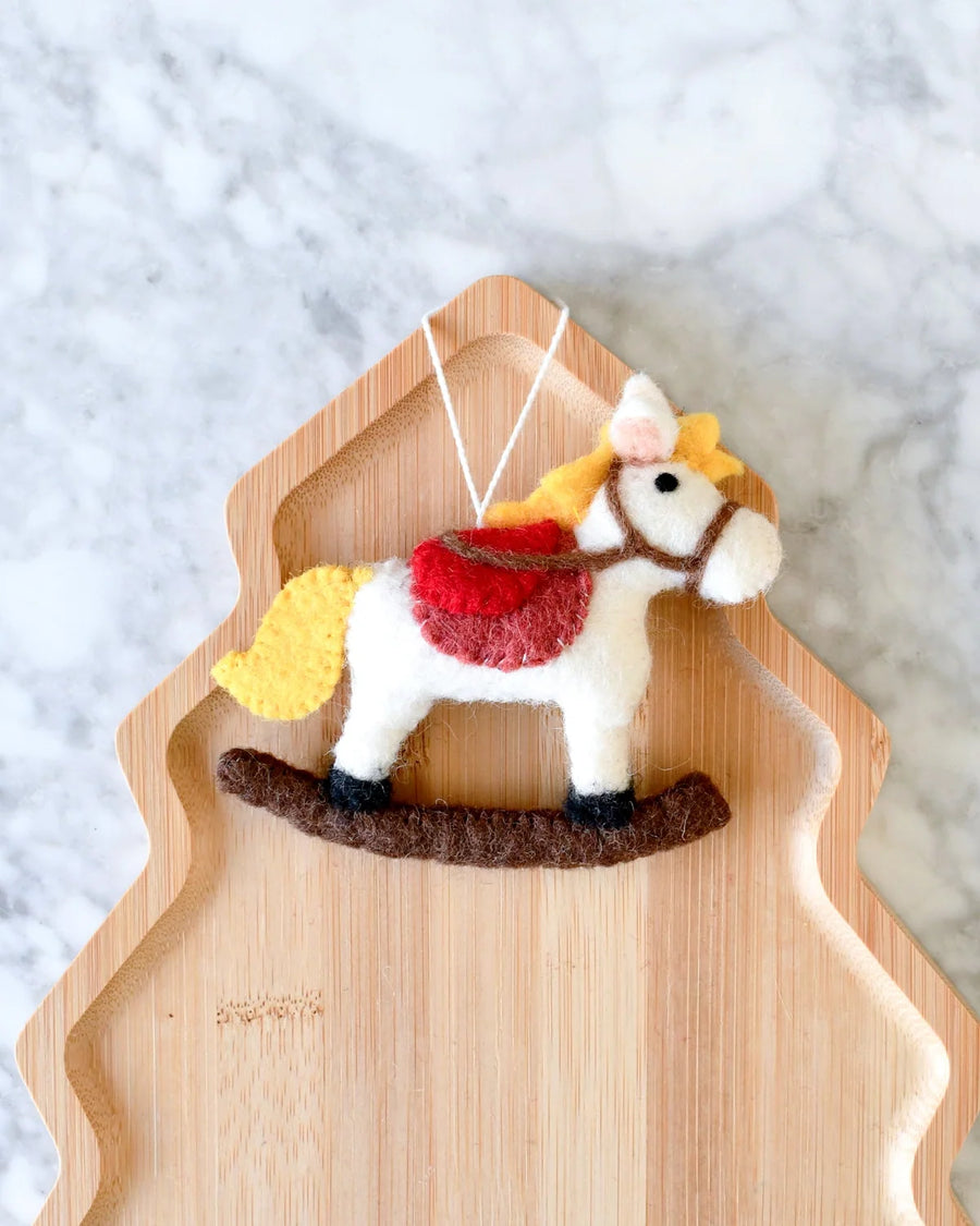 Felt rocking horse ornament, side view, showing the stitched bridle and yellow tail