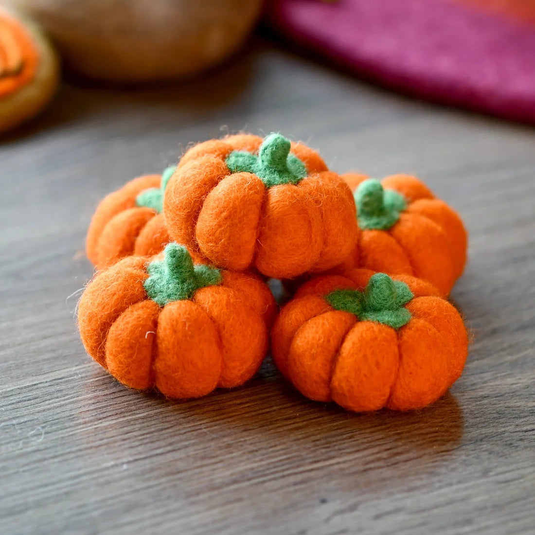 Five small felt pumpkins in bright orange, each with a stitched stem