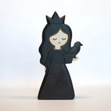 Juharka wooden black princess in a dark gown and pointed crown, holding a small bird in both hands · view 2