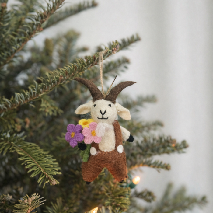 Handmade felt goat ornament in overalls holding a flower bouquet