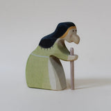 Juharka wooden witch stooped over a walking stick, in a sage green dress with black hair · view 2