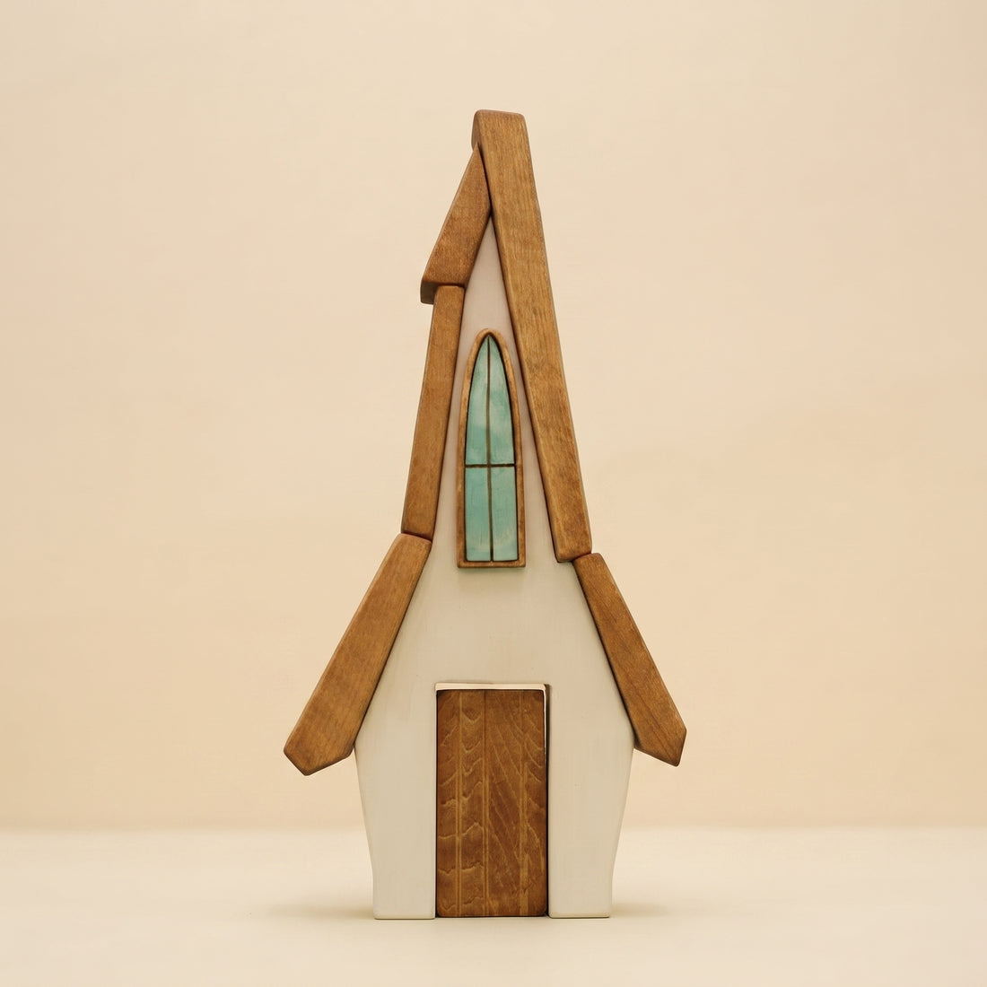 Wooden house with a steep roof, a tall arched window, and a door that lifts out