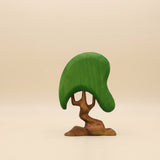 Wooden tree with a broad green canopy on a twisting brown trunk that splits low · view 1