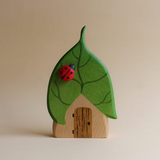Juharka wooden leaf house with a green leaf roof, painted veins, and a red ladybug on top · view 1