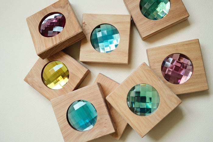 All 8 Bauspiel Giant Sparkling Blocks laid out, each square wooden block holding a large faceted gem in pink, blue, green, yellow and teal