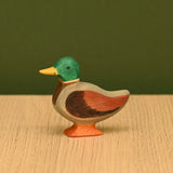 Wooden mallard duck on a wood surface, showing the carved body and painted wing detail · view 3