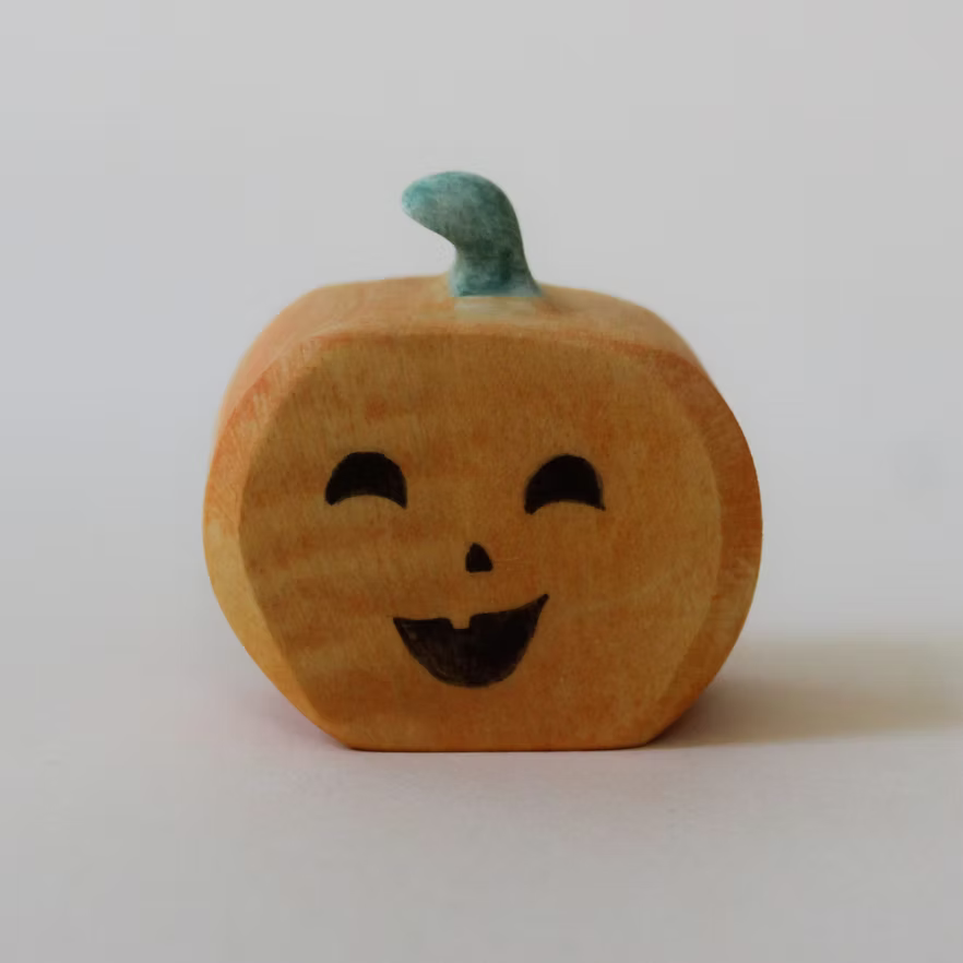 Juharka wooden pumpkin with a winking painted face and a curled green stem